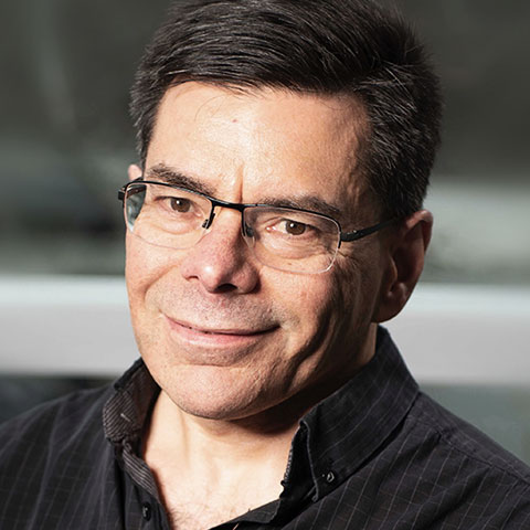 A close-up portrait of Prof. Pelletier, who is smiling and wearing a black button-down shirt