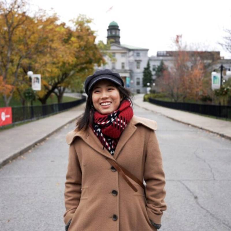 Portrait of a smiling Mai standing in front of the McGill Arts building